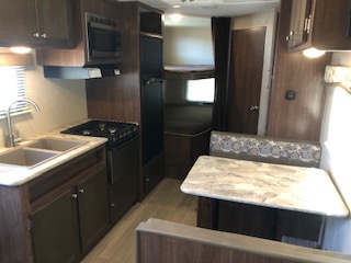 Interior view of a travel trailer, showcasing the living area, kitchen, and sleeping arrangements