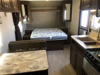 Interior view of a travel trailer, highlighting the living space, furniture, and amenities