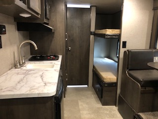 Interior view of a travel trailer, showcasing the living area, kitchen, and sleeping spaces in a compact and functional layout